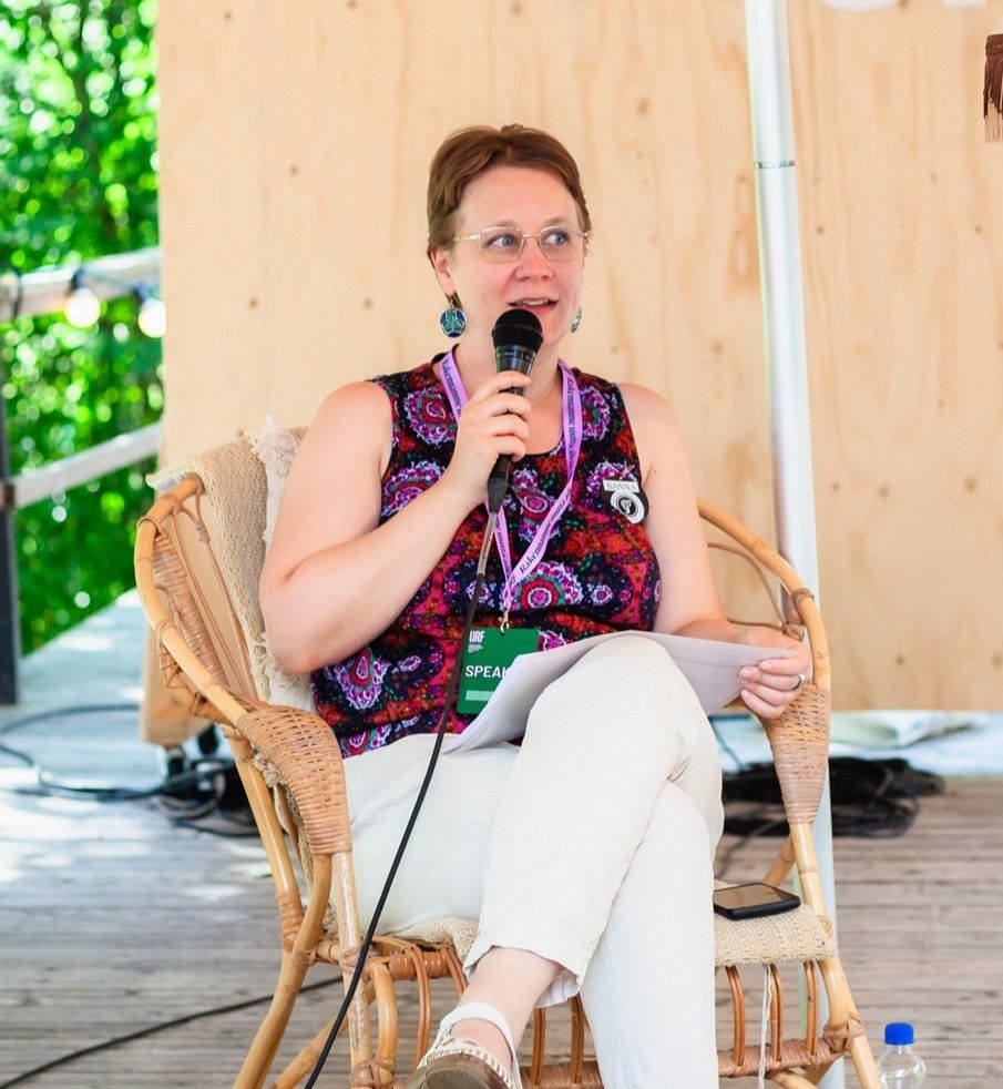 A woman sitting on a chair and speaking to a microphone