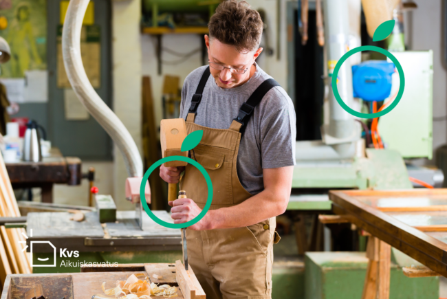 Nuori beesiin työhaalariin pukeutunut miesoletettu kumartuneena työstämään puuta työkalu kädessään taustallaan verstas.