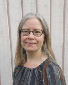 Väljästi rajatussa kasvokuvassa tummasankaisiin silmälaseihin sonnustautunut vaaleahkotukkainen naisoletettu.