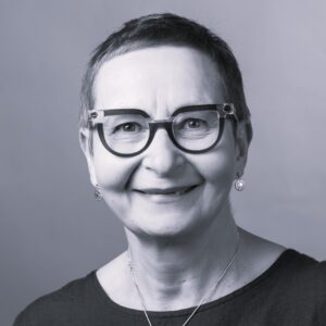 Hymyilevä siilitukkainen silmälasipäinen nainen rajatussa kasvokuvassa